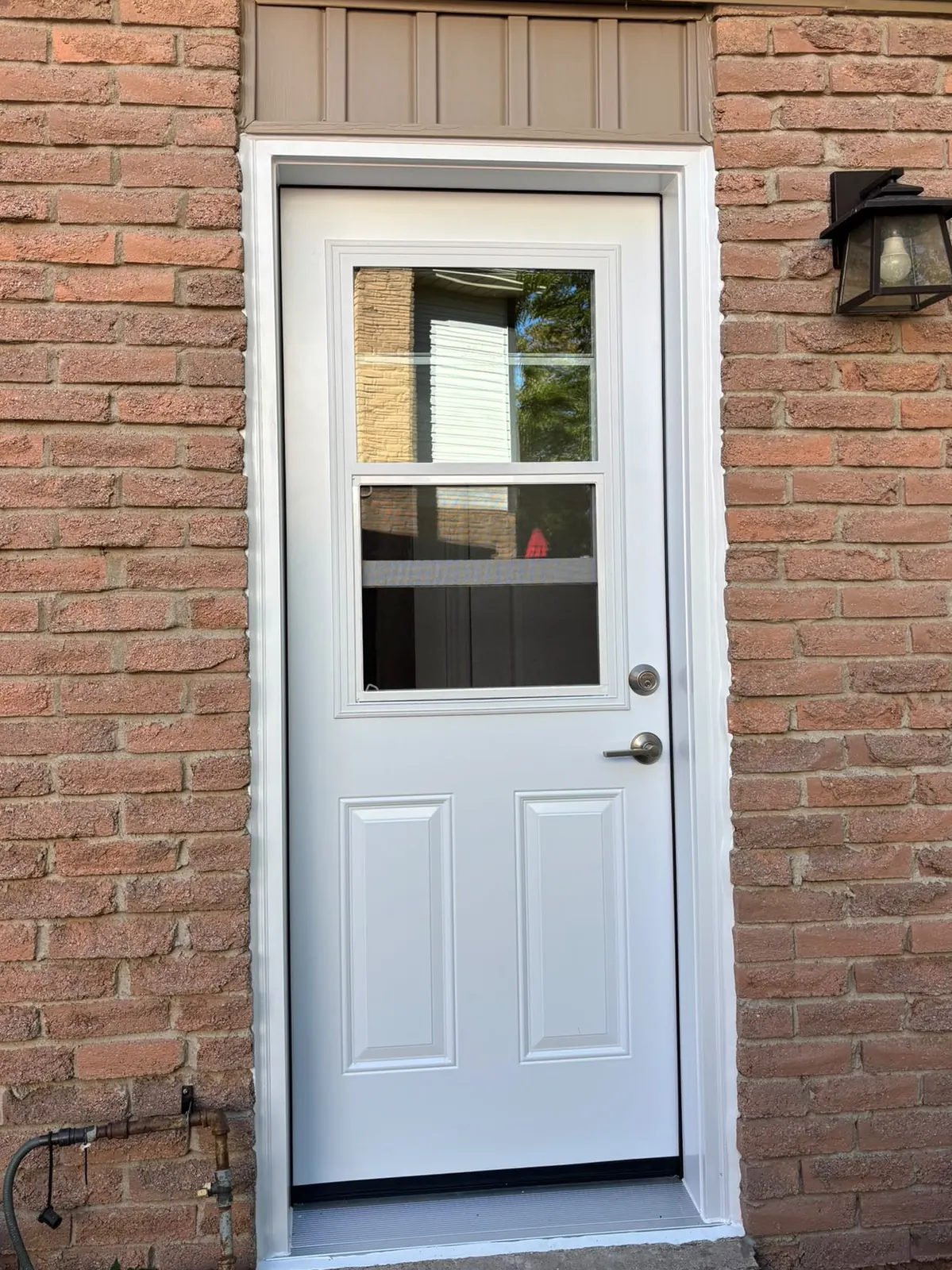 After: new white half-lite back door with fresh trim in the same brick wall