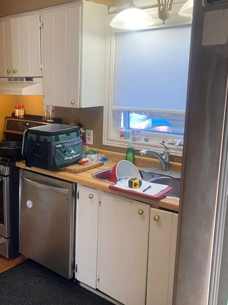 Before: kitchen with oak and white cabinets, a dark mat and an older range