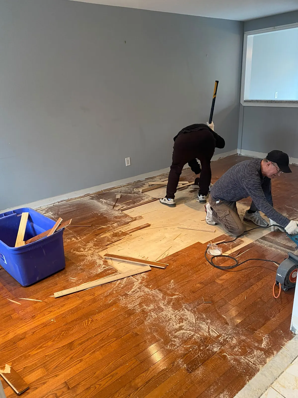 FixRight crew removing old hardwood flooring in a living room